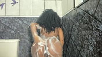 Unclothed young woman of African descent taking a shower