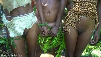 In the middle of the forest, two young women from an African tribe are having a good time with the chief of the village.